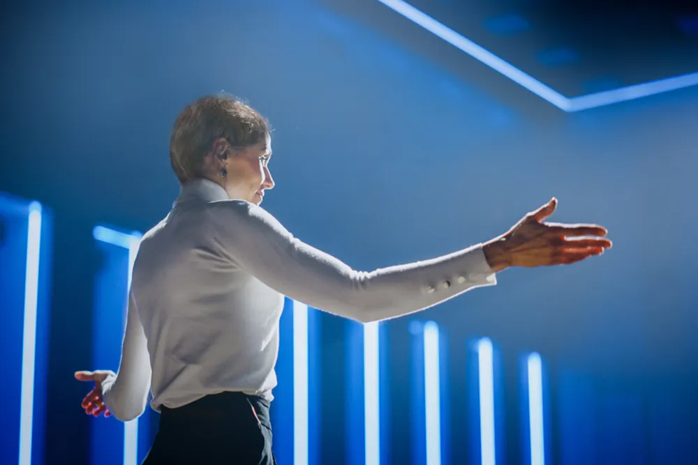 Karol Hines standing with arms outstretched with blue lights in background