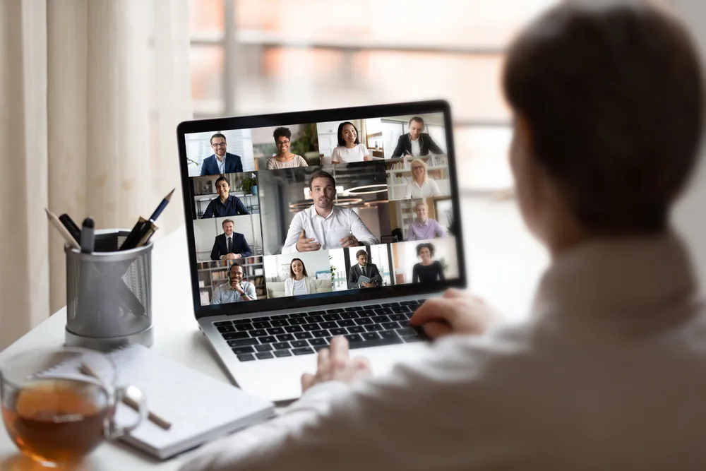 woman at desk interacting with laptop on video conference